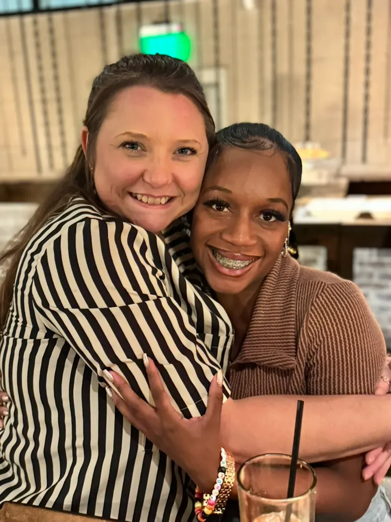 Two colleagues embracing and smiling at a social event, representing collaborative technology services, technology management, and the Elevate Technology mobile team.